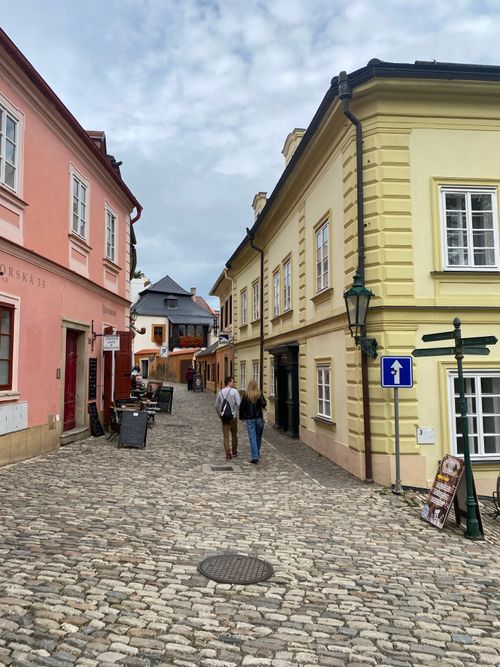 Free Picturesque cobbled street in Europe with colorful historic buildings and two people walking. Stock Photo