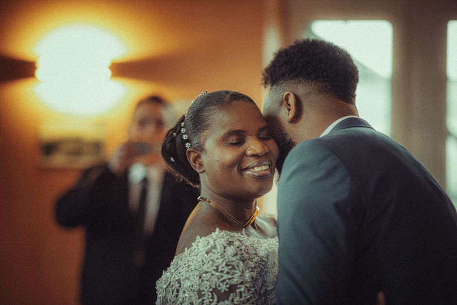 A bride and groom share a joyful moment during their wedding ceremony, captured indoors.