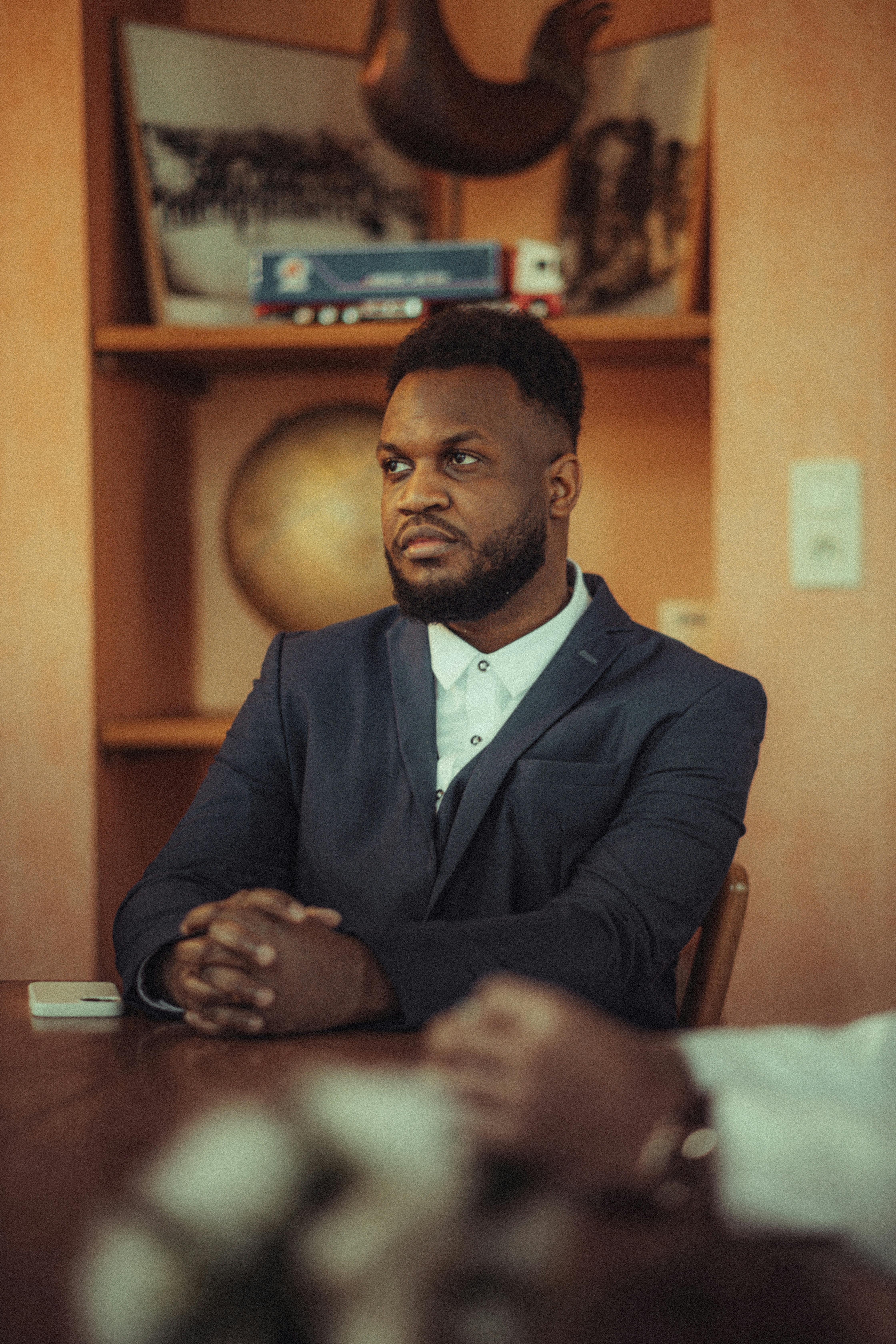 A professional businessman in a suit, seated at a table during a meeting.