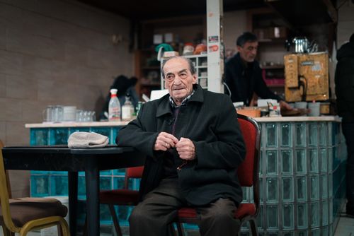 Free An elderly man sits comfortably in a cozy coffee shop, enjoying the warm atmosphere. Stock Photo