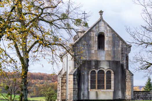 A serene view of a historic stone chapel surrounded by autumn trees in Switzerland.