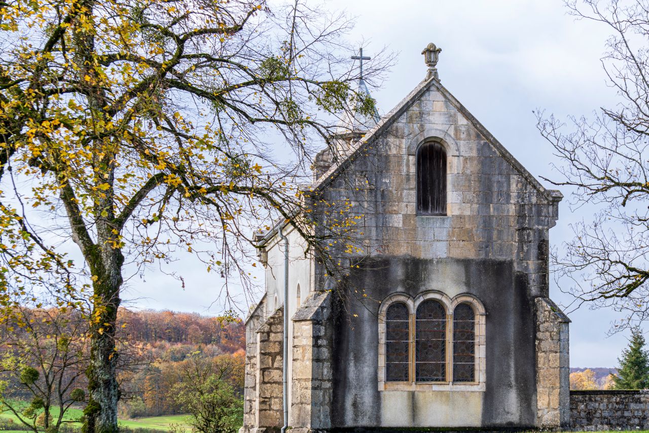 a serene view of a historic stone chapel surrounded by autumn trees in