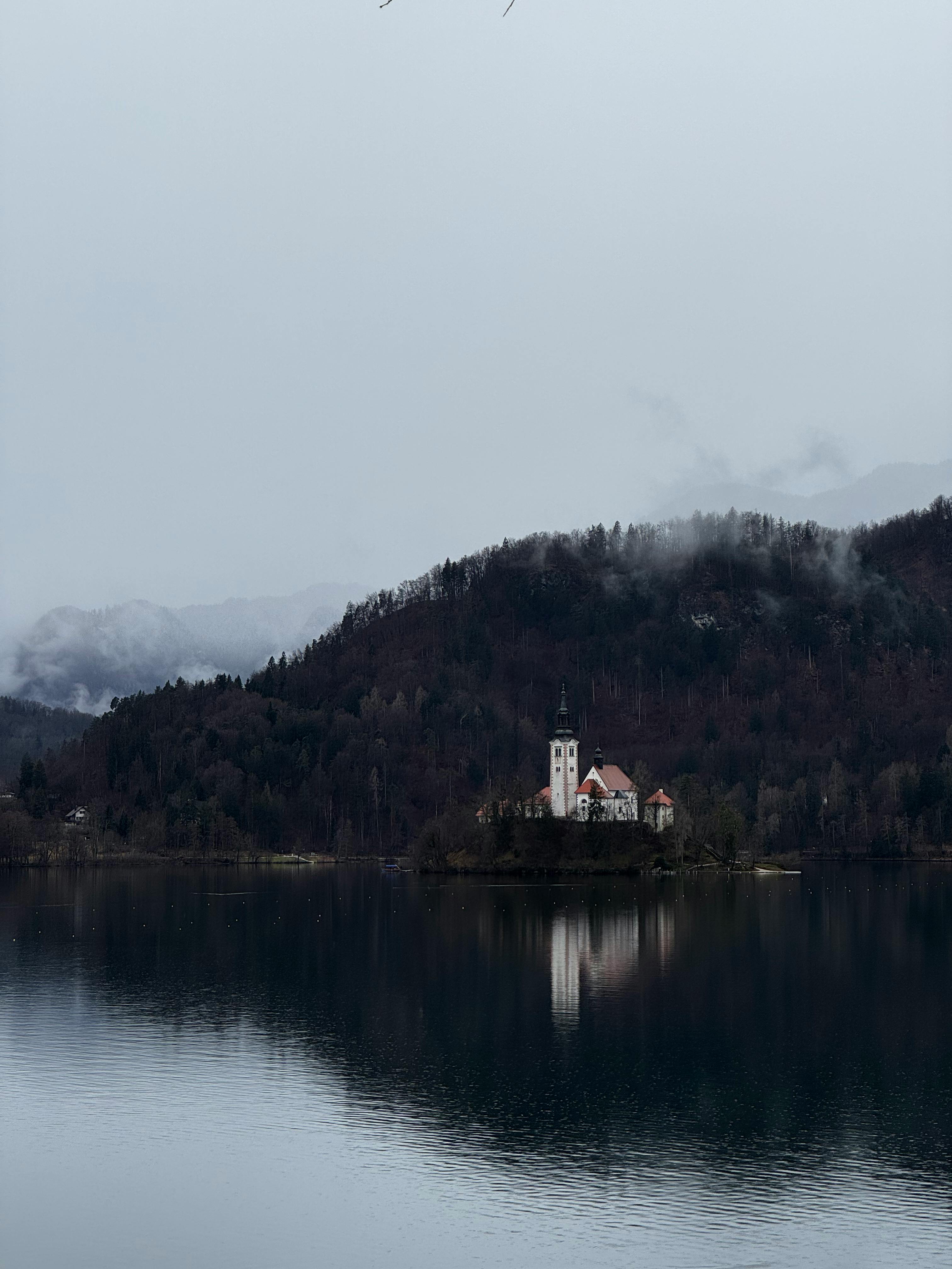 Atmospheric photo of Lake Bled with the church on the island surrounded by misty mountains.