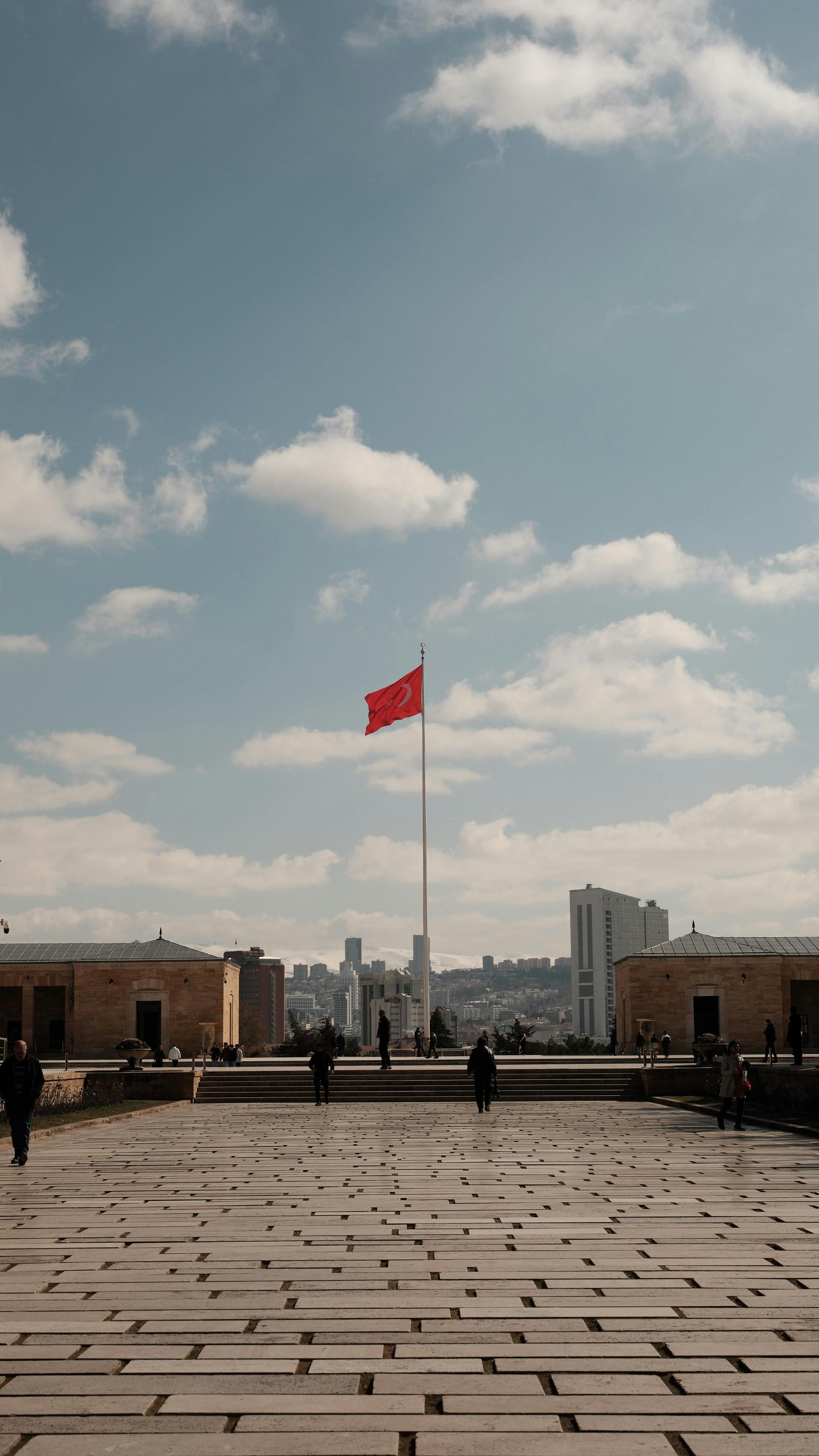 Anıtkabir and Turkish flag against Ankara city skyline on a clear day.