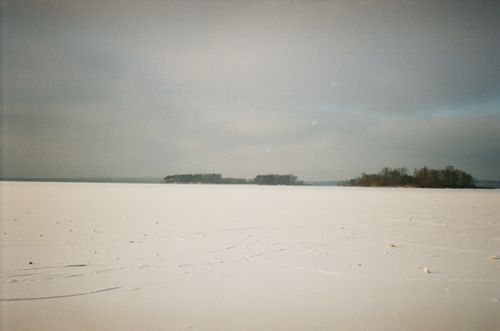 Free Peaceful snowy landscape featuring a frozen lake under a cloudy winter sky. Stock Photo