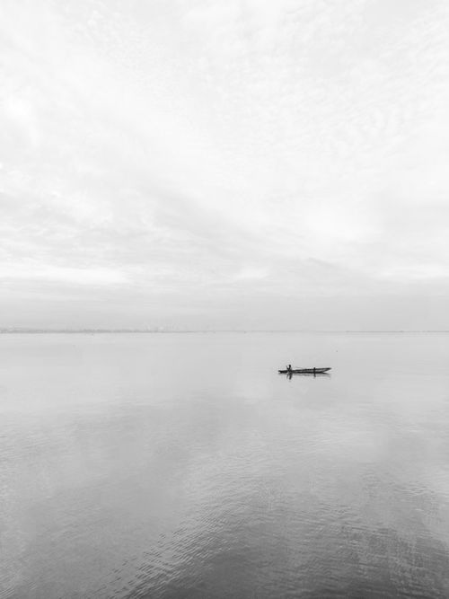 Free A serene and minimalist black and white photograph of a lone boat on tranquil water in the Philippines. Stock Photo