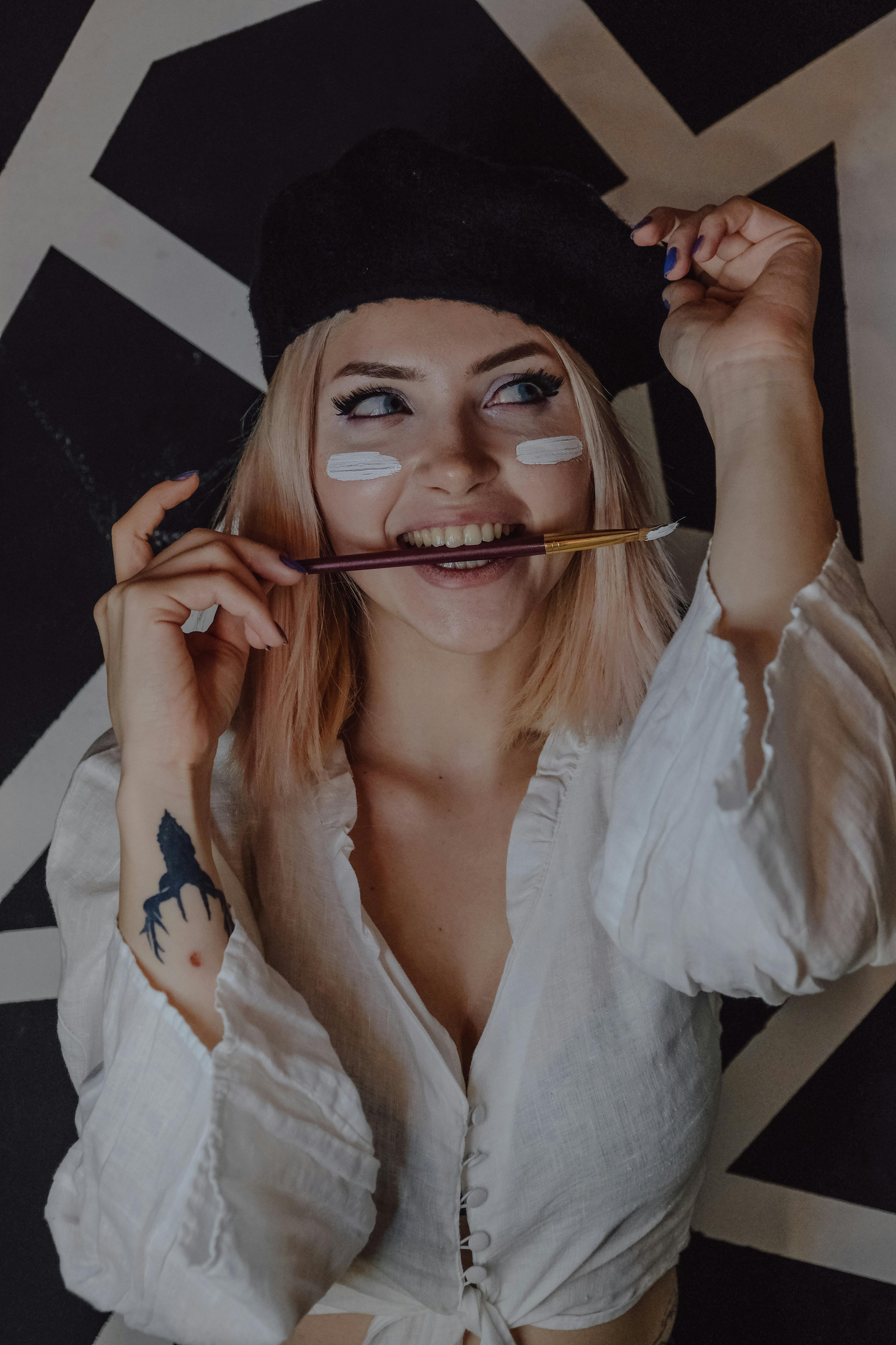 Miễn phí Một nữ nghệ sĩ trẻ với khuôn mặt đầy màu sắc, đang cầm cọ, thể hiện sự sáng tạo và phong cách. Ảnh lưu trữ