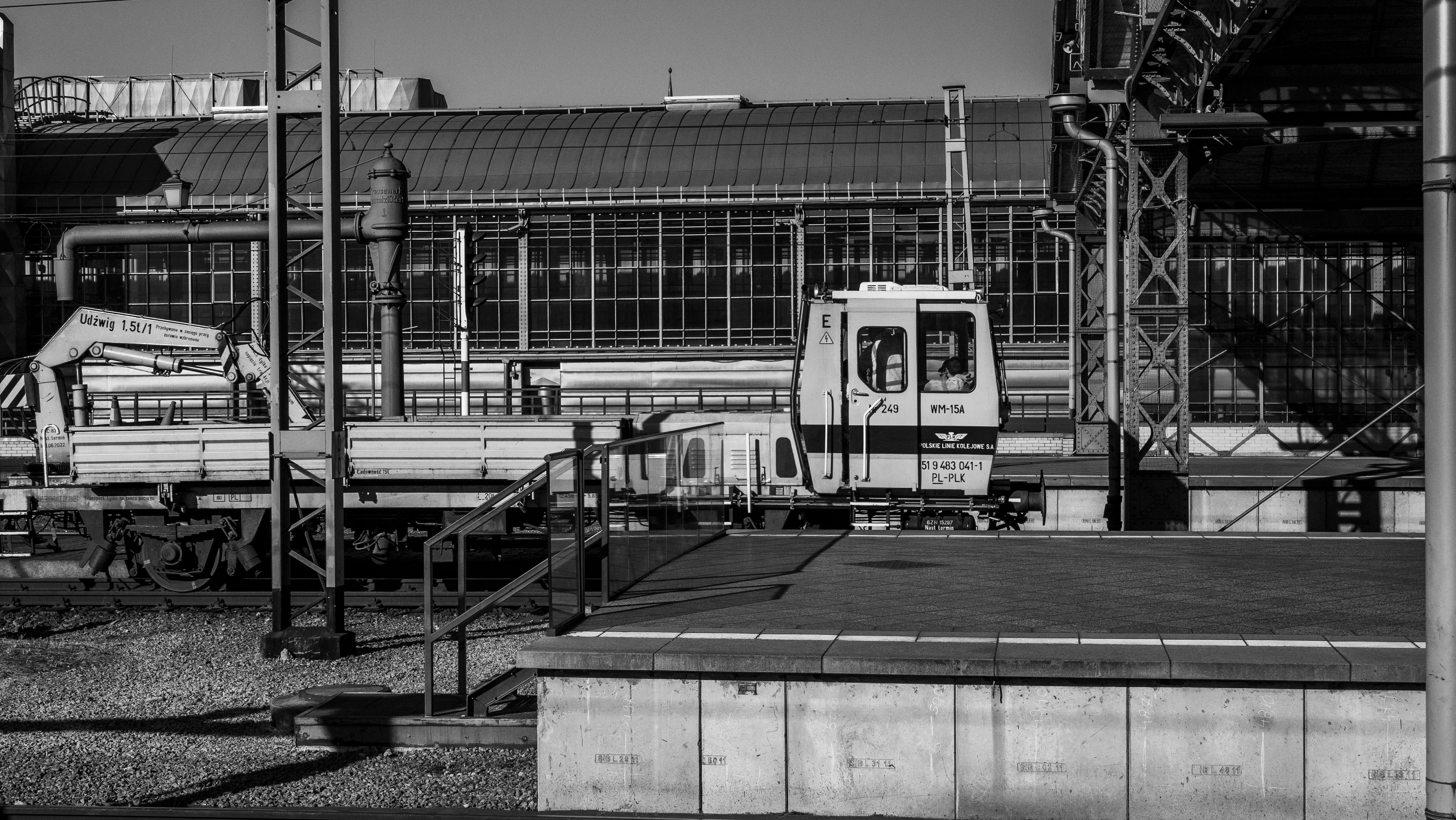 Monochrome image of an empty industrial train station with tracks and scaffolding.