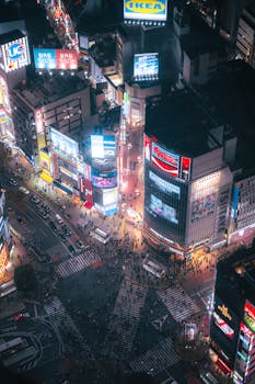 Aerial shot of the bustling and iconic Shibuya Crossing in Tokyo, illuminated at night.