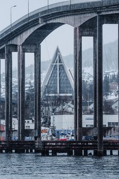 A breathtaking view of Tromsø Bridge with the iconic Arctic Cathedral in Tromsø, Norway, during winter.