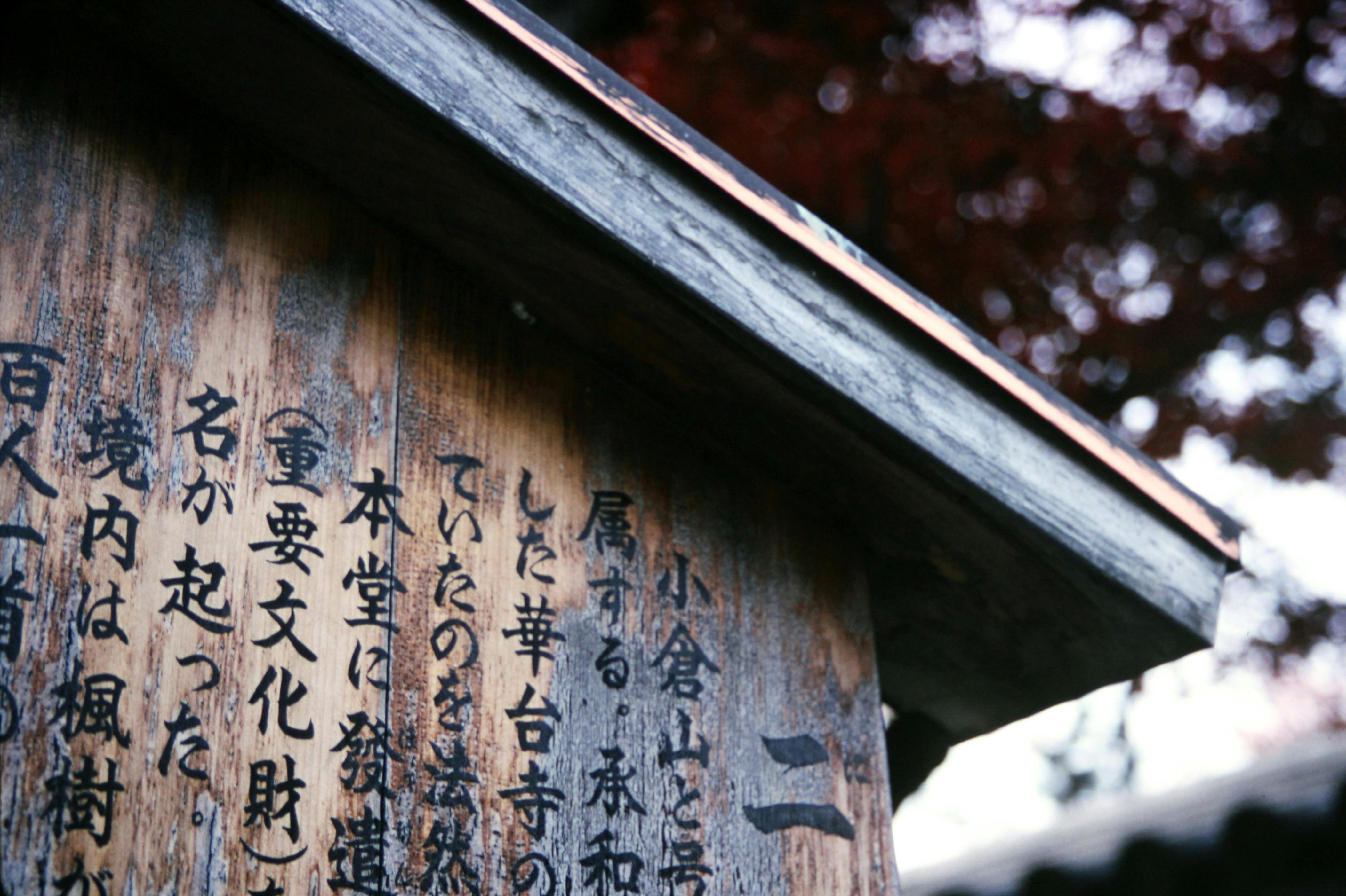 A close-up of a weathered wooden sign featuring Japanese kanji characters, adds cultural depth.