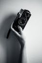 Vintage Camera in Hand Against White Wall