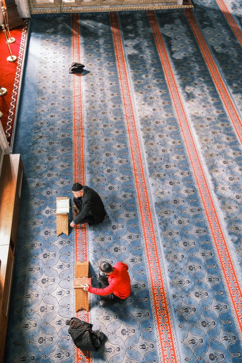 Free Two men studying on a beautifully patterned mosque floor seen from above. Stock Photo