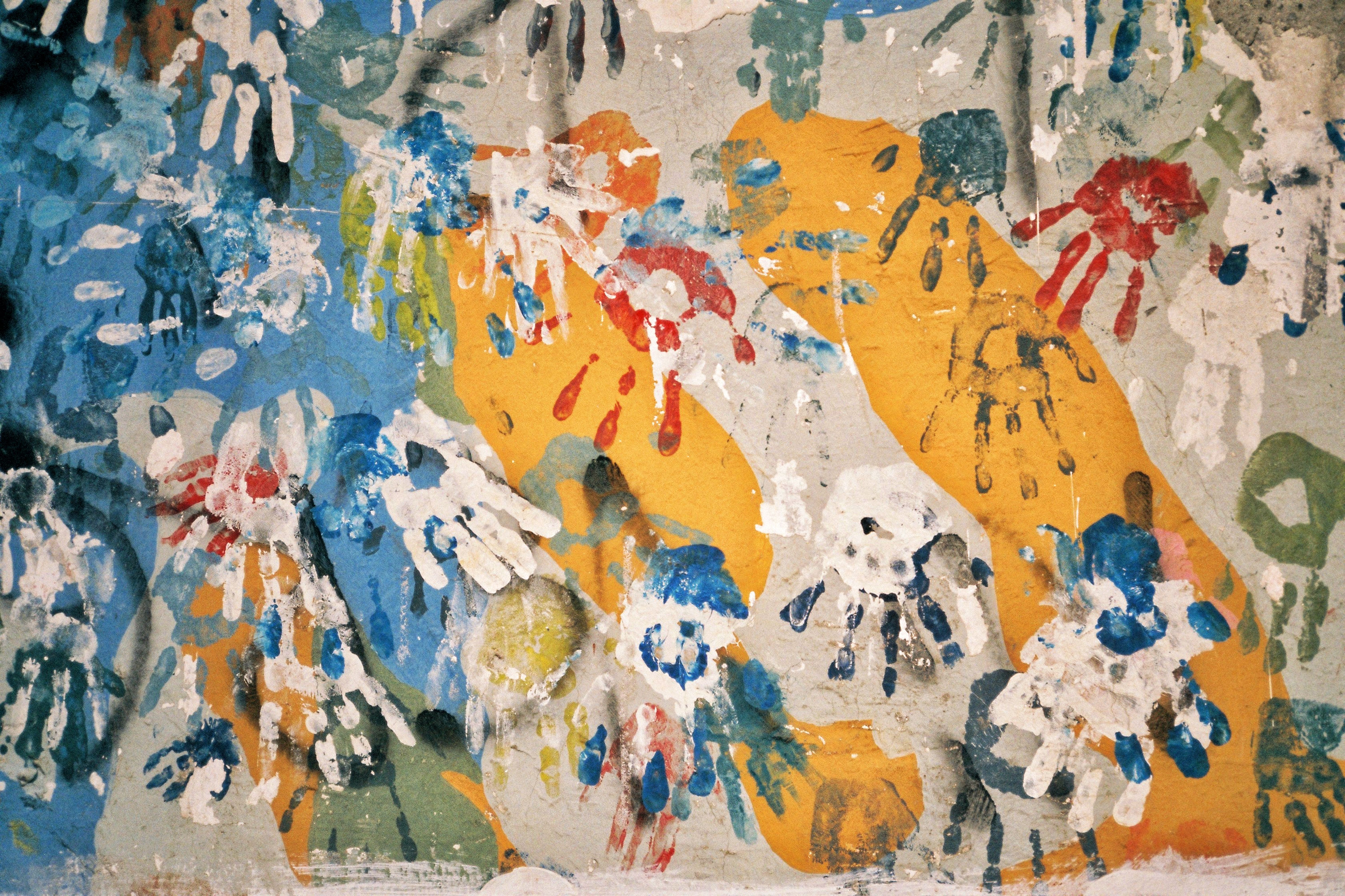 A lively display of colorful handprints on a textured urban wall, showcasing street art creativity.