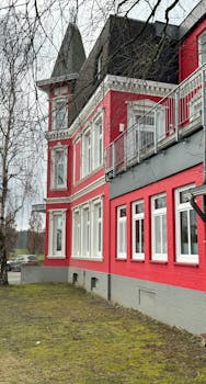 Historic red brick building with turret and bare trees in a winter landscape.