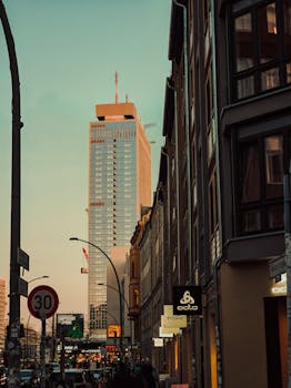 Berlin street view of modern skyscraper and historic buildings at dusk, blending old and new architecture.