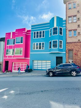 A bright city street showcasing vivid pink and blue urban houses with modern designs.