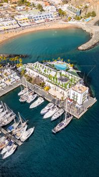 Stunning aerial shot of a vibrant port in the Canary Islands with yachts and scenic beaches.