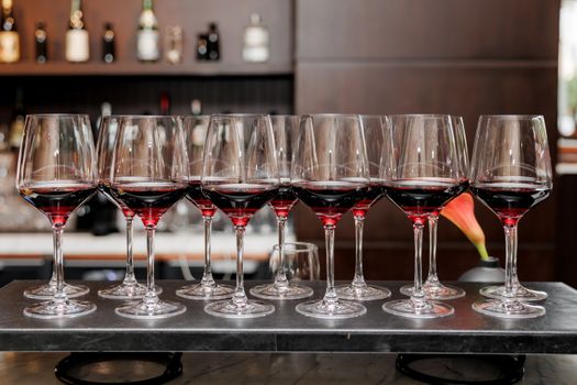 Calici di vino rosso allineati sul bancone di un bar