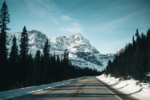 Free Snowy road leading to majestic mountain peaks in Jasper, Alberta. Stock Photo