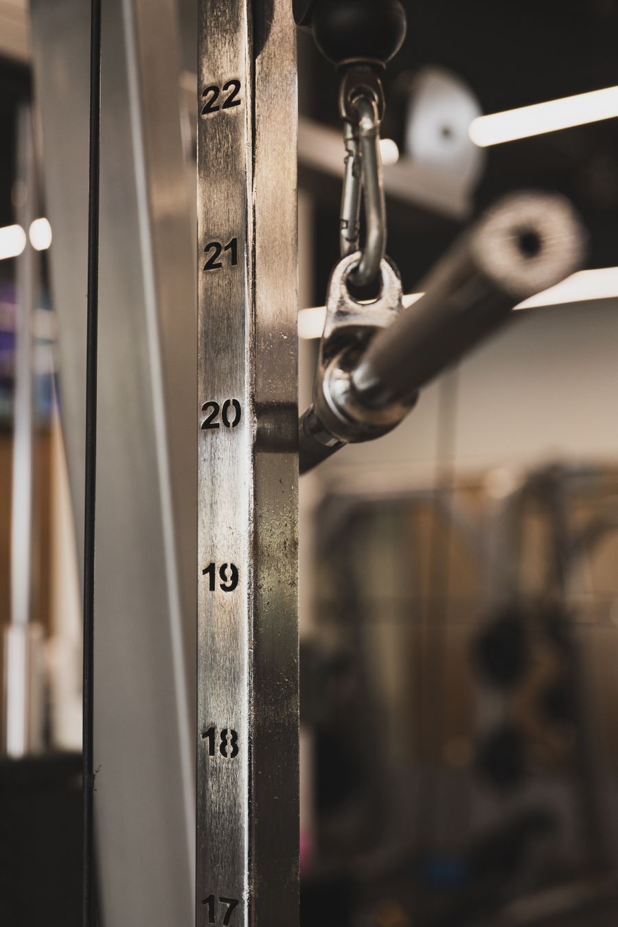 Close-up of a cable machine weight stack with numbered plates and selector pin for strength training