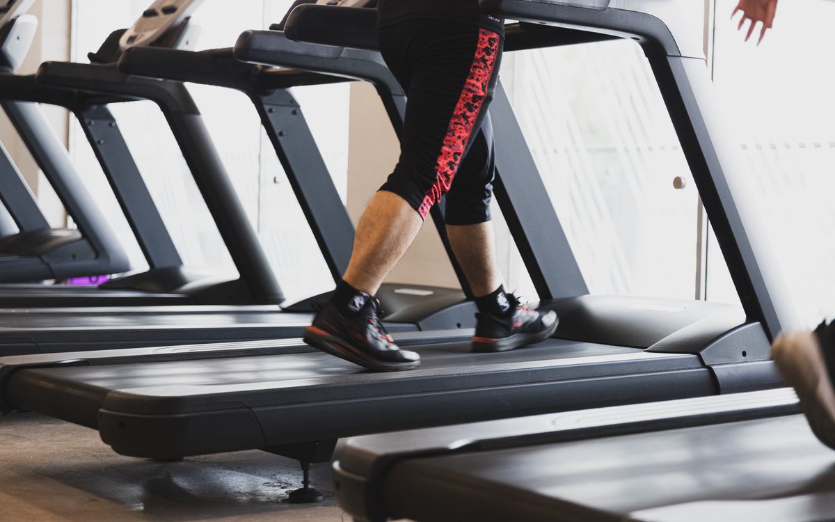 A person walking on a treadmill in a modern gym setting, focusing on fitness.
