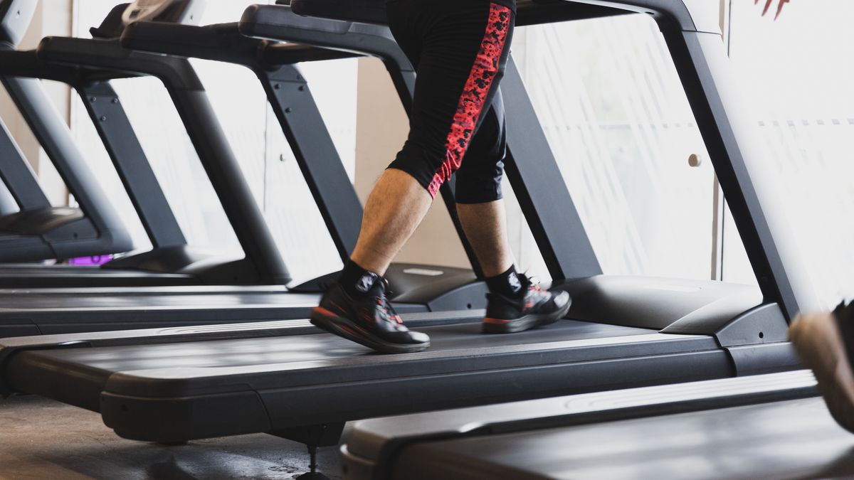 A person walking on a treadmill in a modern gym setting, focusing on fitness.