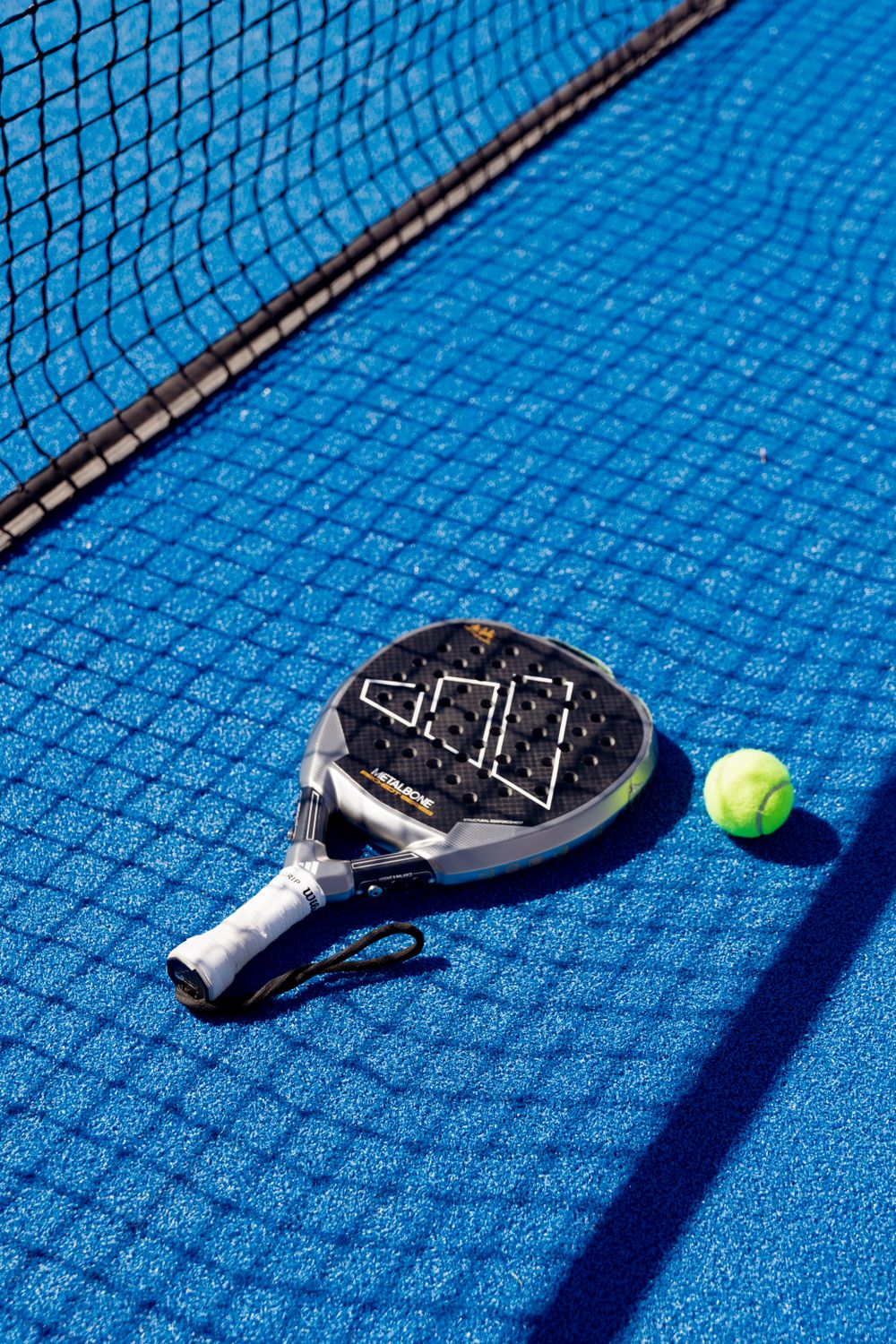 Nox AT10 Luxury Padel-Schläger mit Ball auf blauem Court