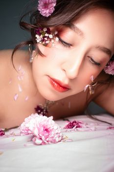 Close-up portrait of woman with floral makeup and petals, creating artistic look.
