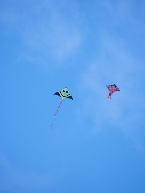 Free Two vibrant kites flying in a clear blue sky, evoking a sense of freedom and joy. Stock Photo