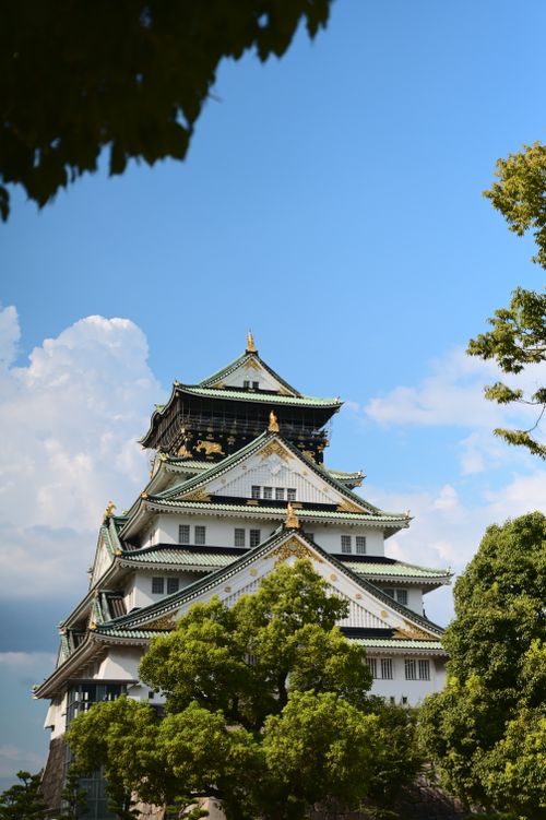 Free A beautiful sunny day view of Osaka Castle surrounded by lush trees. Stock Photo