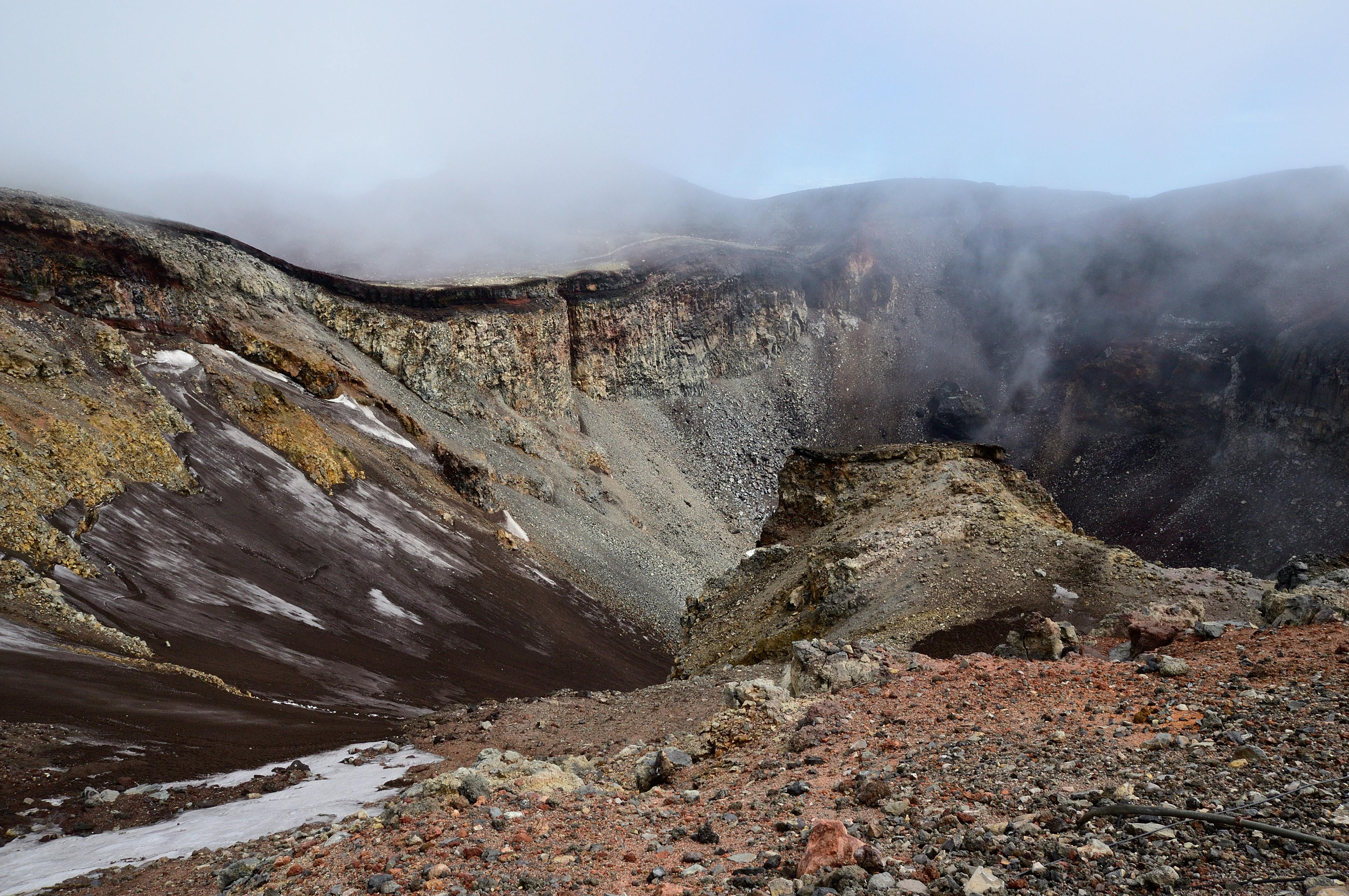Explore the awe-inspiring volcanic crater surrounded by mist in this dramatic landscape.