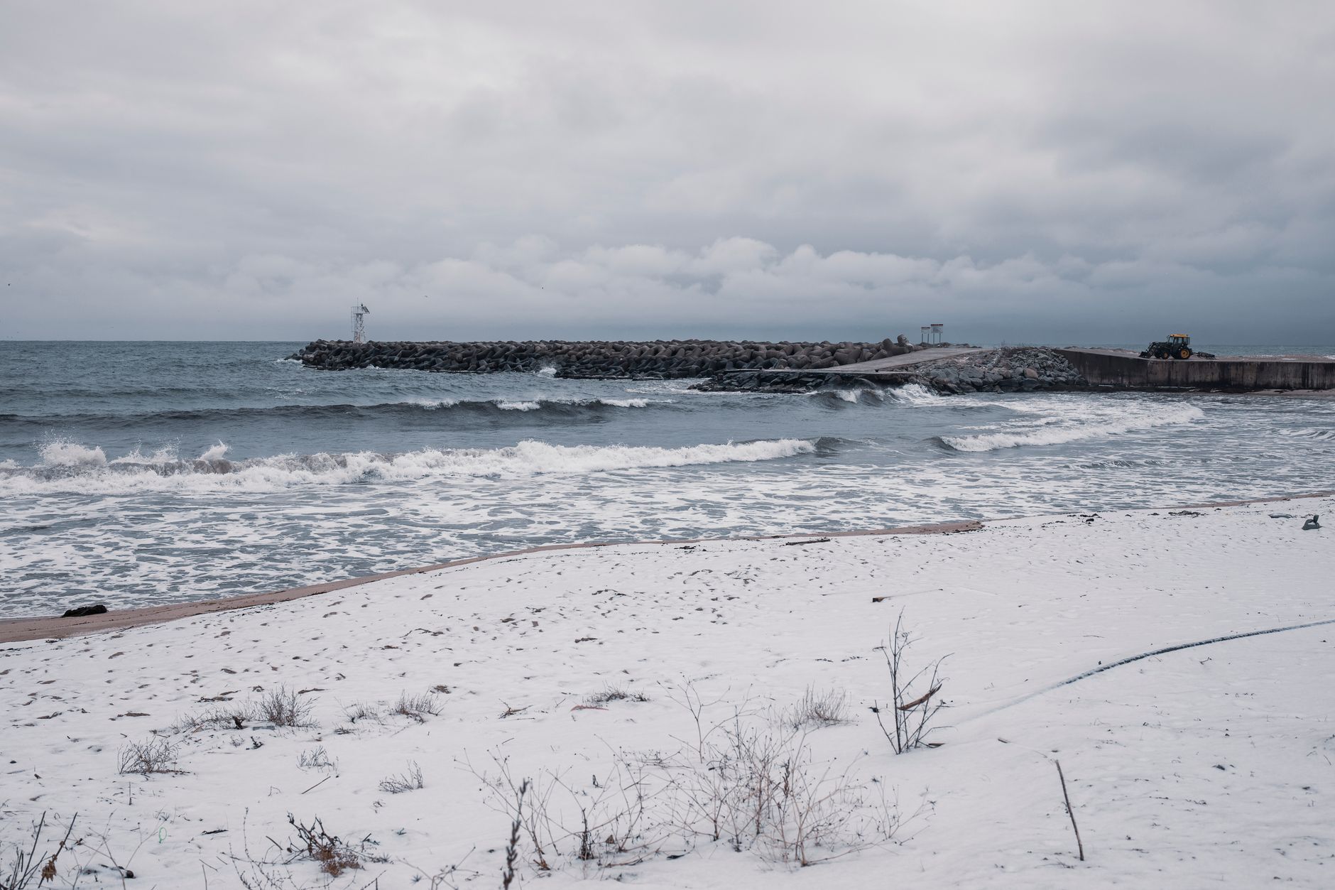 Empty winter beach at Paphos with cafe chairs stacked and a grey sea