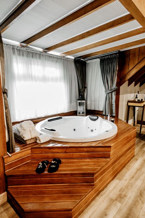 Free Elegant indoor spa featuring a modern wooden bathtub with luxurious amenities, perfect for relaxation. Stock Photo
