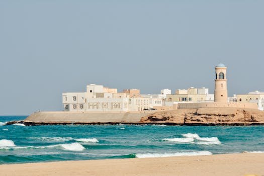 A serene view of Sur Lighthouse and traditional buildings on the Omani coast.