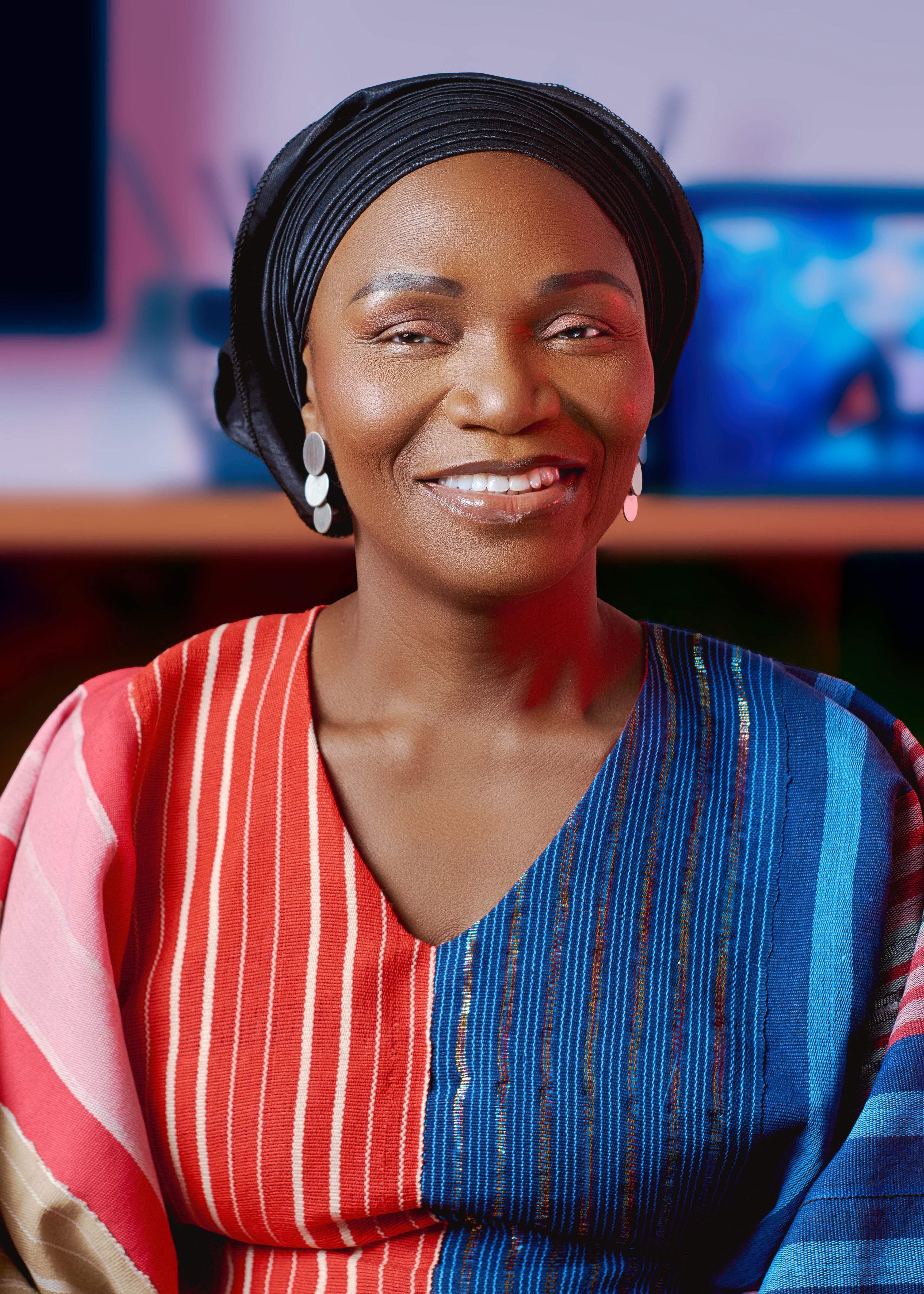 Smiling woman in colorful Nigerian attire, showcasing cultural beauty.