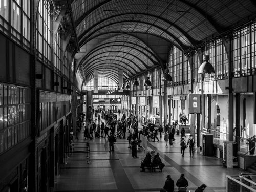 Free Busy train station interior with commuters in black and white. Stock Photo