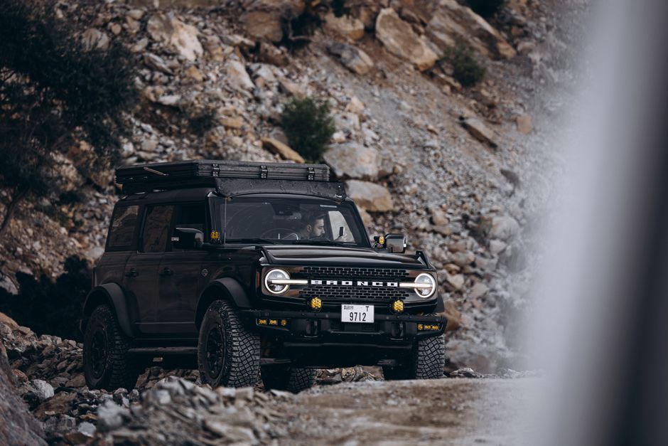A 4x4 vehicle navigating rugged terrain in the Hajar Mountains of Oman.