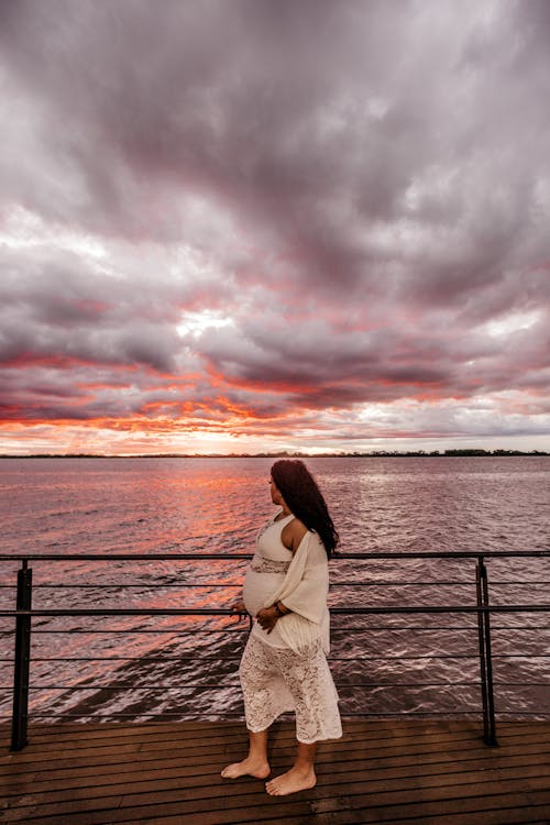 бесплатная Фотография беременной женщины, стоящей на берегу залива Стоковое фото