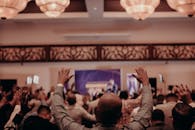 在灯光明亮的室内场地，充满活力的人群举起双手，捕捉着集体能量的瞬间