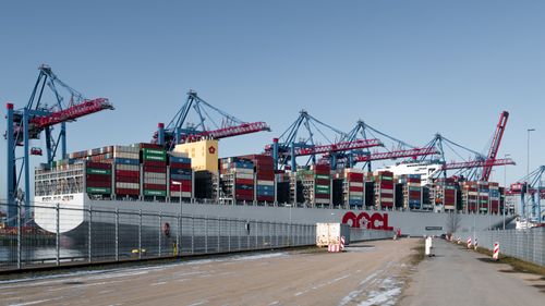 Free A container ship docked at a bustling shipping terminal in Hamburg, Germany. Stock Photo