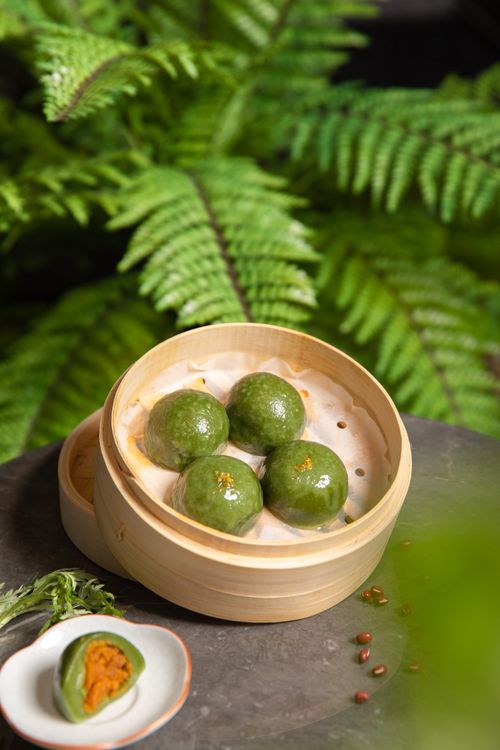 Free Green tea mochi in a bamboo steamer surrounded by lush ferns. Stock Photo