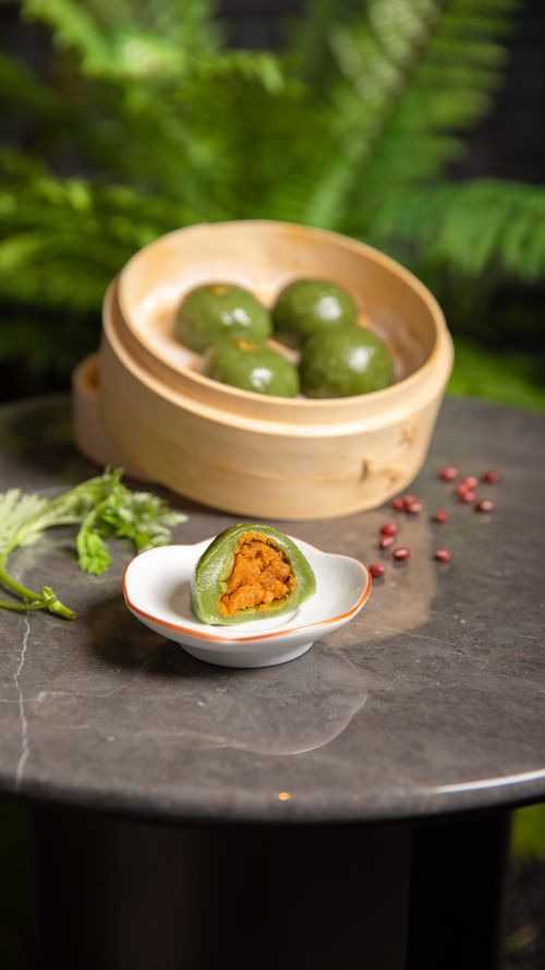 Free Green Chinese sweet dumplings with red bean paste on a marble table, surrounded by lush ferns. Stock Photo