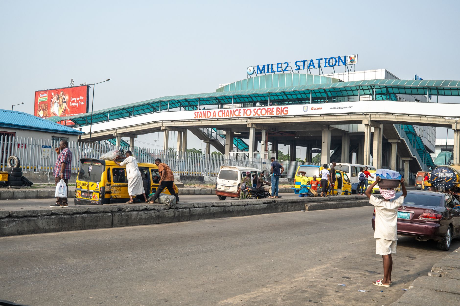 Street view of Mile 2 Station in Lagos, capturing urban life and commuters.