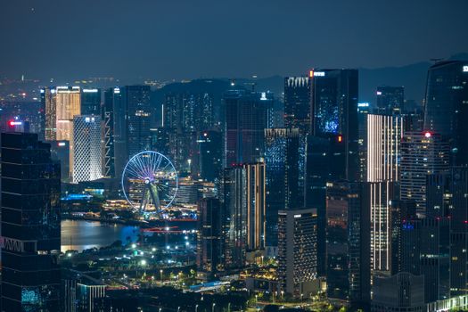 Dynamic city skyline illuminated at night featuring a striking Ferris wheel and skyscrapers.