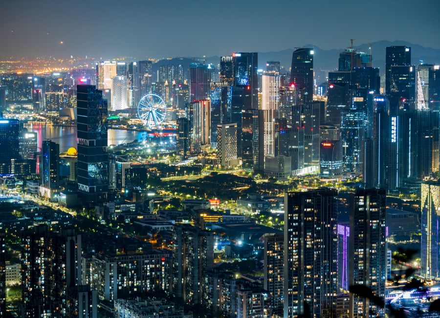 Dazzling city skyline illuminated at night showcasing modern skyscrapers and a Ferris wheel.