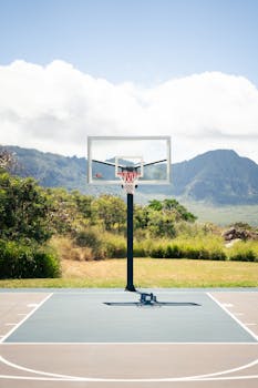 Outdoor basketball court with stunning mountain backdrop on a sunny day.