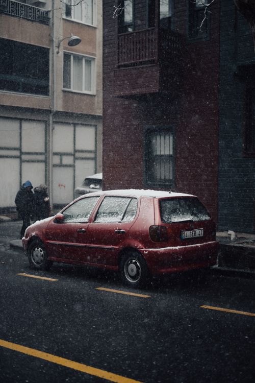 Free A red car parked on a snowy street in Kuzguncuk, Istanbul, capturing a moody cinematic ambiance. Stock Photo