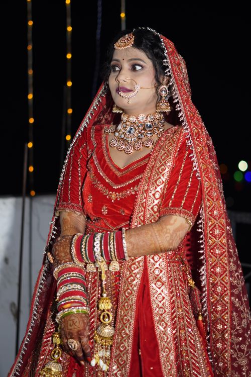 Free Stunning Indian bride wearing red lehenga and intricate jewelry at a wedding ceremony. Stock Photo