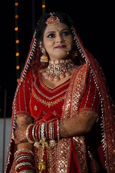 Beautiful Indian bride in red and gold lehenga, adorned with intricate jewelry.